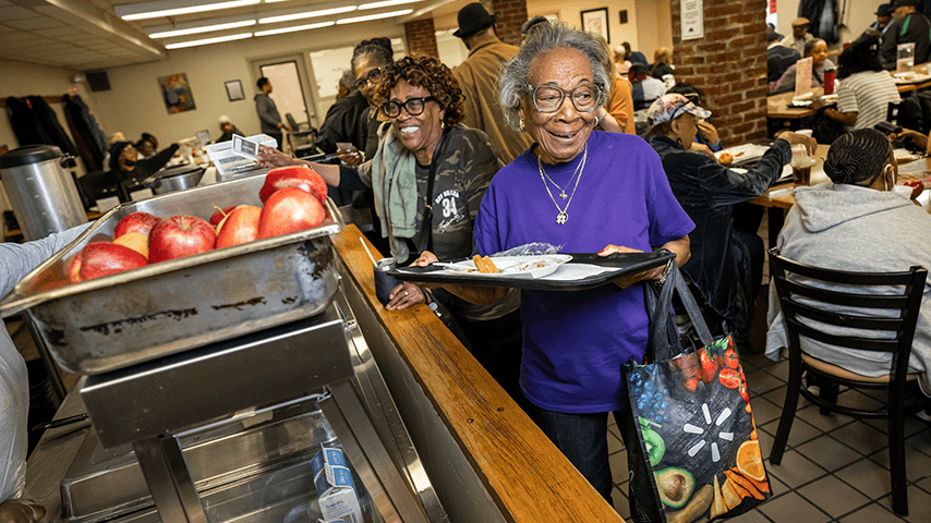 smiling older adults with food trays in senior center cafeteria