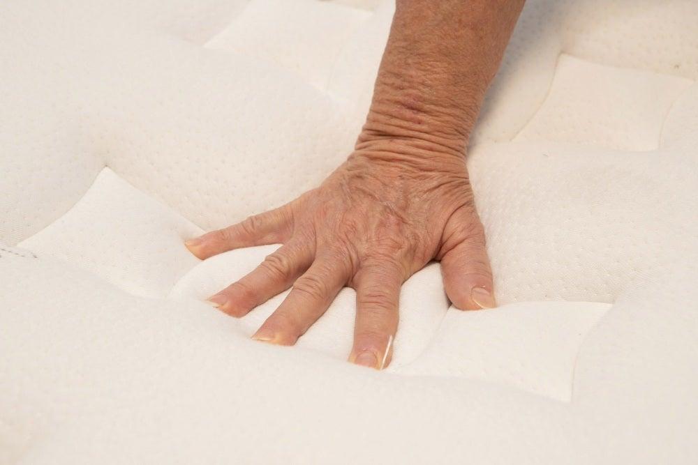 A hand pressing into the plush top of the Nolah Evolution mattress