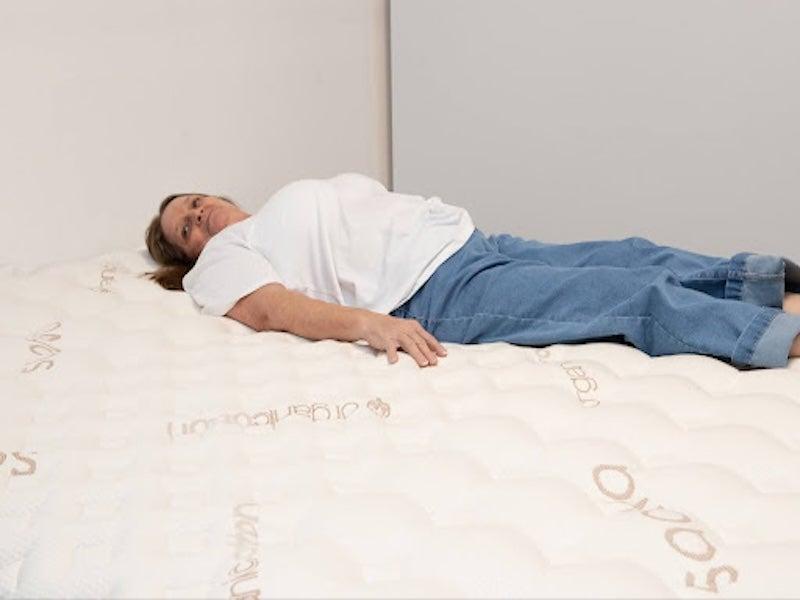 A woman lies on her back on the Saatva Rx mattress.