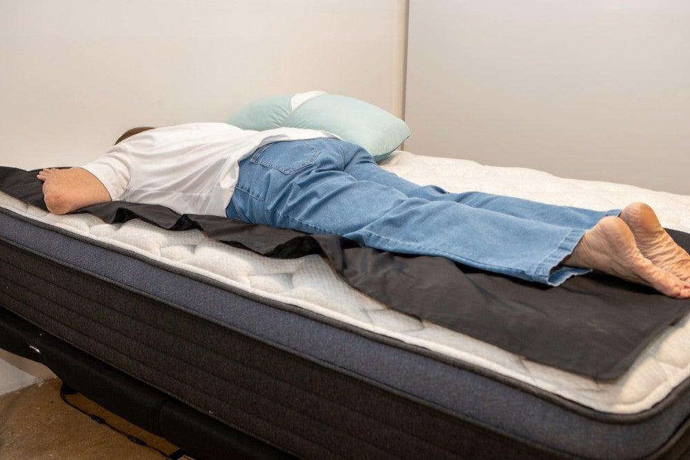 An older woman lying on her stomach on a pressure map laid over the Helix Midnight Luxe