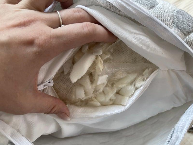 A hand holding the inside of the Layla Kapok pillow open to see its filling