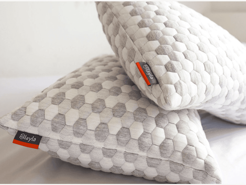 Two fluffy pillows with a hexagonal design and tags showing “Layla” logo.