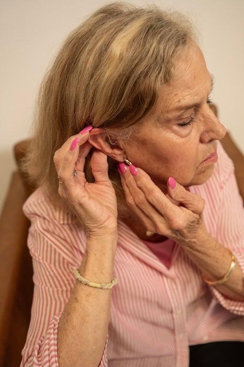 A woman places the Concha Sol hearing aid in her ear
