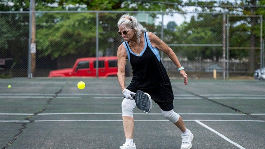 A person winds up to hit a pickleball.