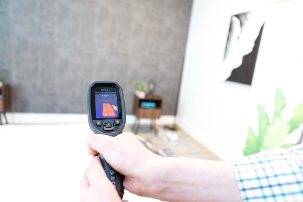 A hand holding a heat gun pointed at the mattress.