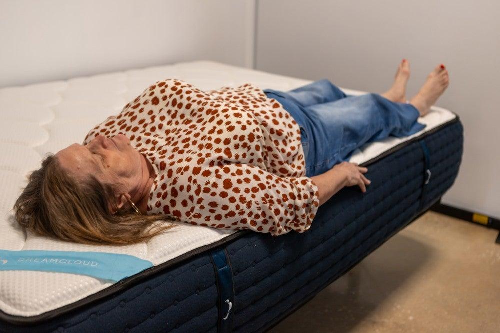 A woman lying on her back near the edge of the DreamCloud Premier mattress