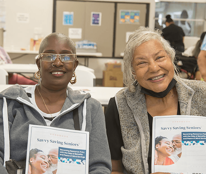 two smiling older black women holding Savvy Saving Seniors guides