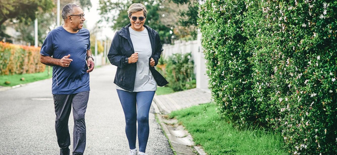 A senior Black couple is outside power walking in their neighborhood. Regular exercise can help slow or prevent bone loss as well as boost muscle strength.