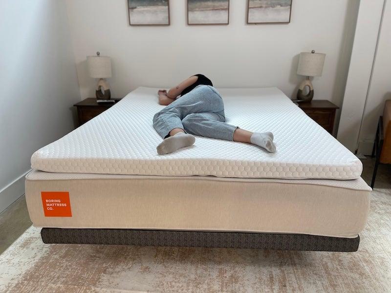 A woman lies on her side on the Bear Pro mattress topper