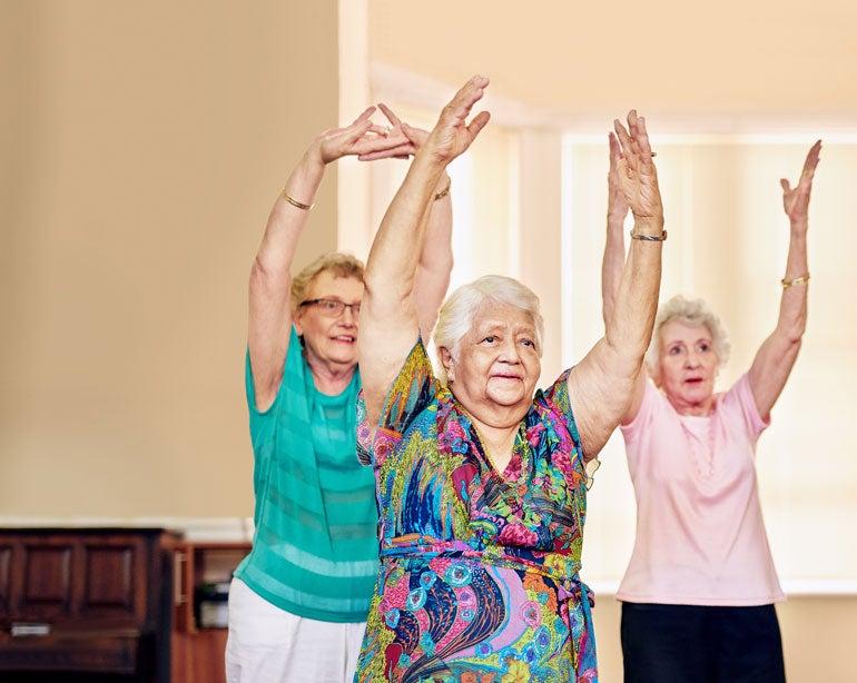 Three senior women are exercising indoors together.
