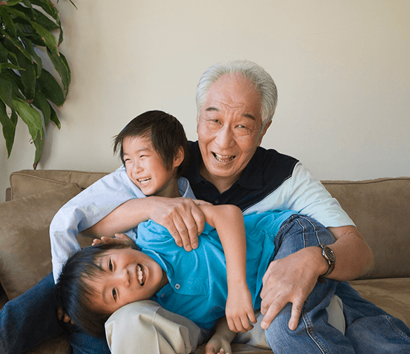 Asian grandfather playing with two laughing grandchildren