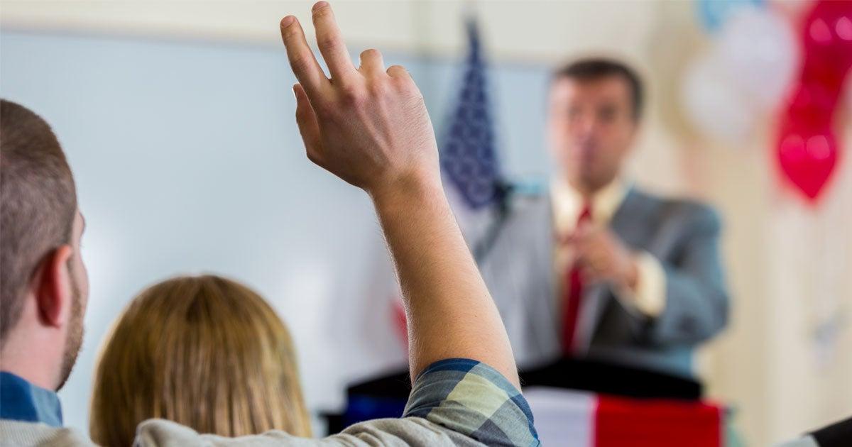 An advocate for older adults raises his hand at a town hall.