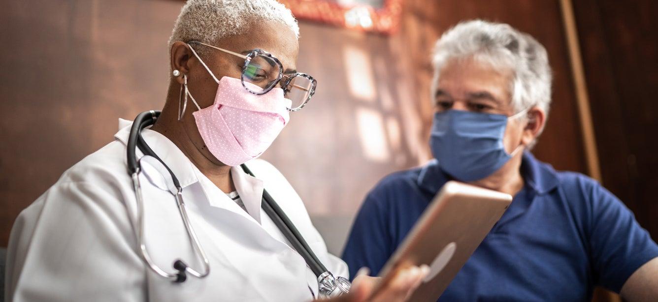 A senior Black woman doctor is talking to a caucasian man about his health care options.
