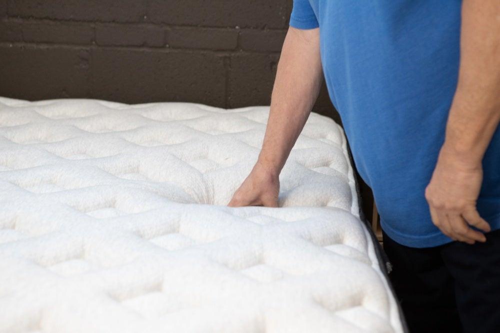 A man pressing down on the Helix Midnight Luxe’s pillow top layer