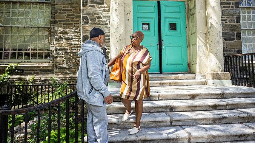 Black older man and woman talking on the steps of a senior center