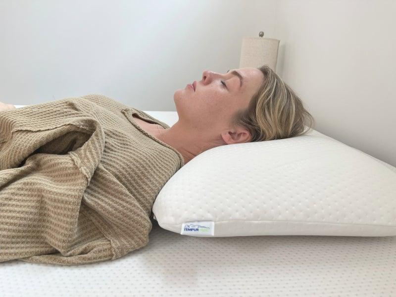 A woman sleeps on her back with a TEMPUR-Symphony pillow.