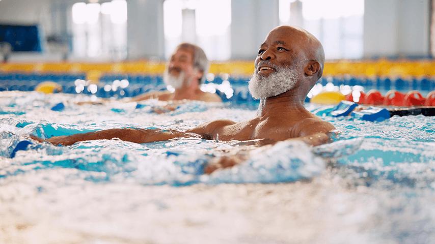 older black man with gray beard smiling while exercising in pool