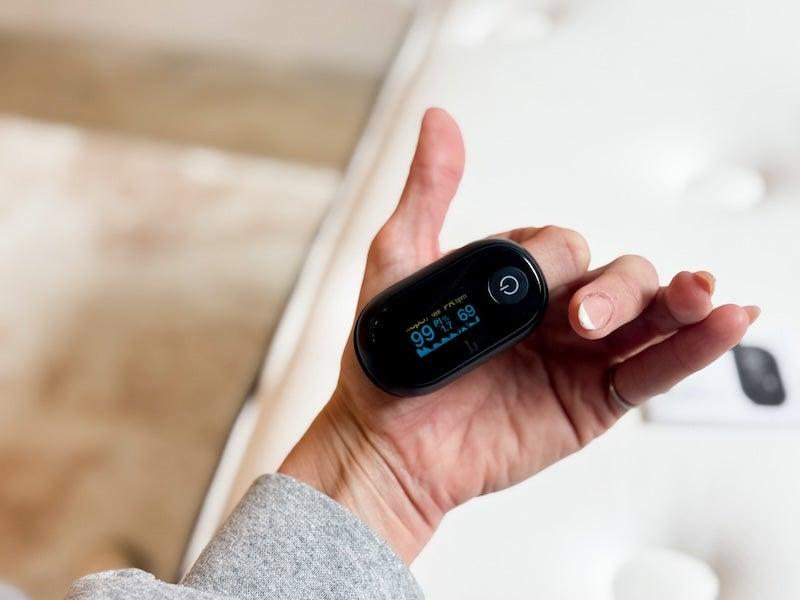 A woman wears the Oxiline 9S Pro on her fingertip.