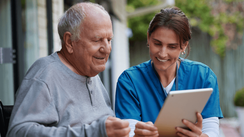 An older man and a nurse look at a tablet together