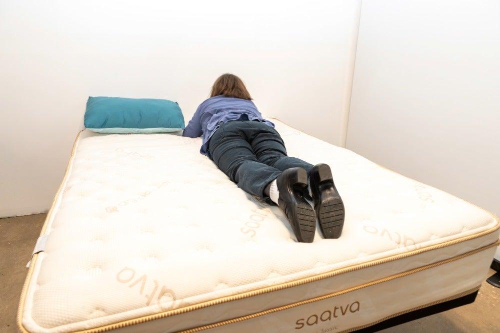 A woman lies on her stomach on a bed facing away from the camera