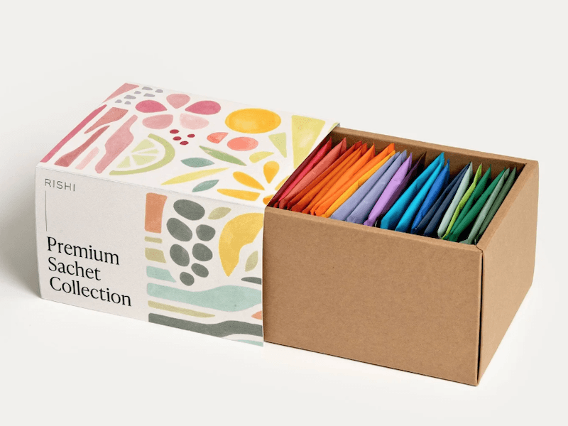 Box of tea with tea bags in brightly colored, individually wrapped bags; side of box reads “Rishi Premium Sachet Collection”