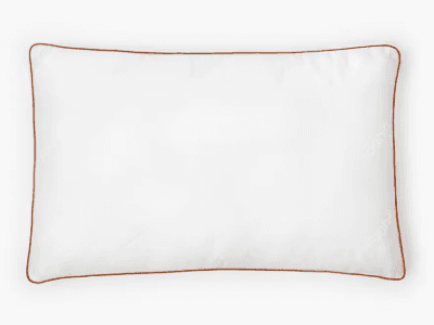 A rectangular, white Saatva latex pillow with dark gold trim