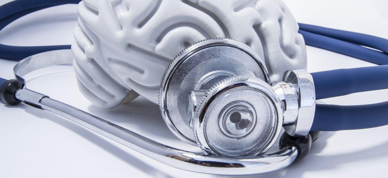 An up close shot of a model plastic brain surrounded by a stethoscope.