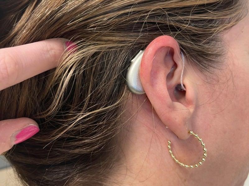 A woman wearing the Elehear Beyond hearing aids, showing the way they fit behind the ear