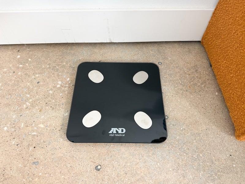 The A&D Medical Bluetooth Body Composition Scale, a black square of glass with white anti-slip footies