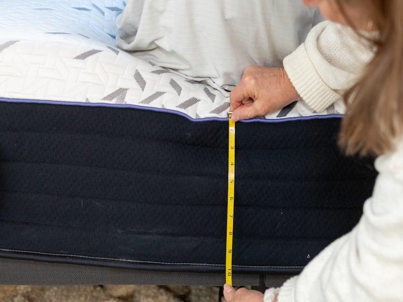 A woman measures the mattress height.