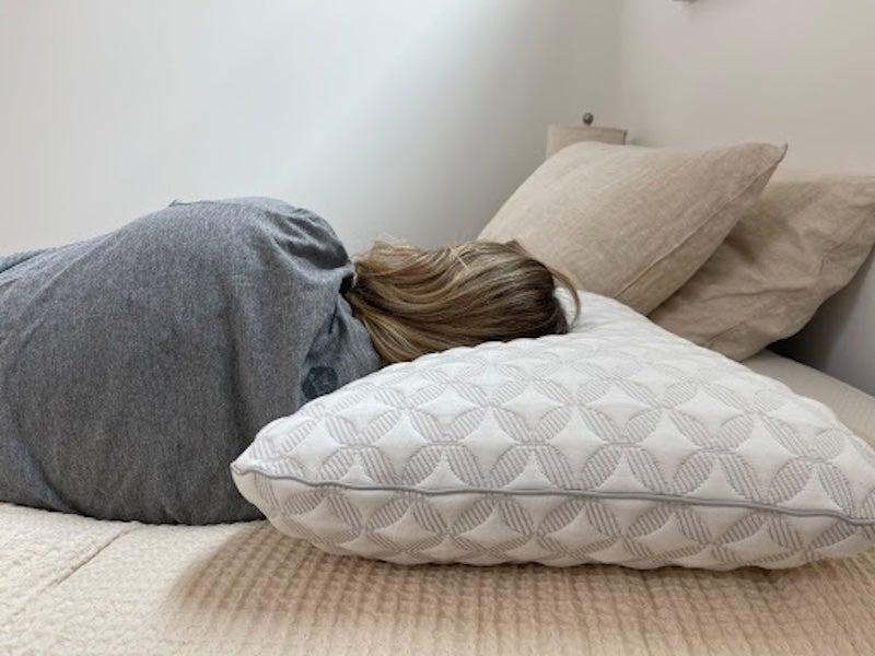 A woman lies on her side on the Brooklyn Bedding Talalay Latex pillow.