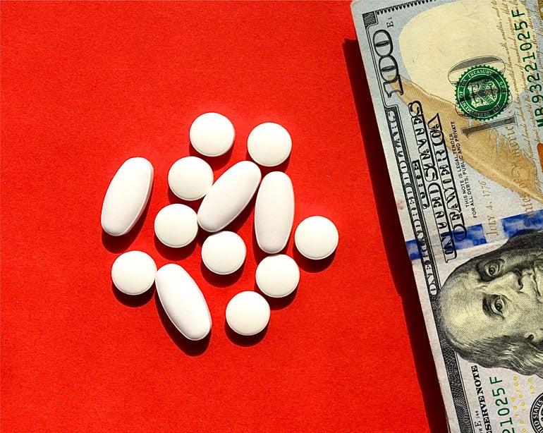 A handful of prescription bills sit next to a stack of U.S. money.