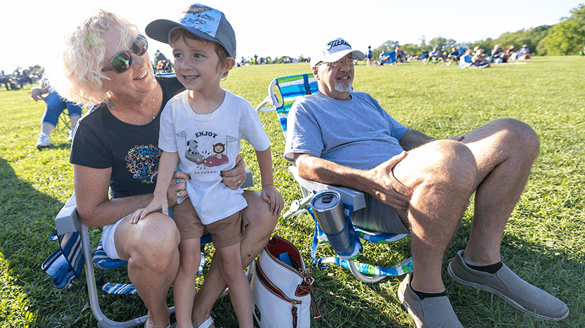 smiling grandmother with young grandson and grandfather in lawn chairs in field