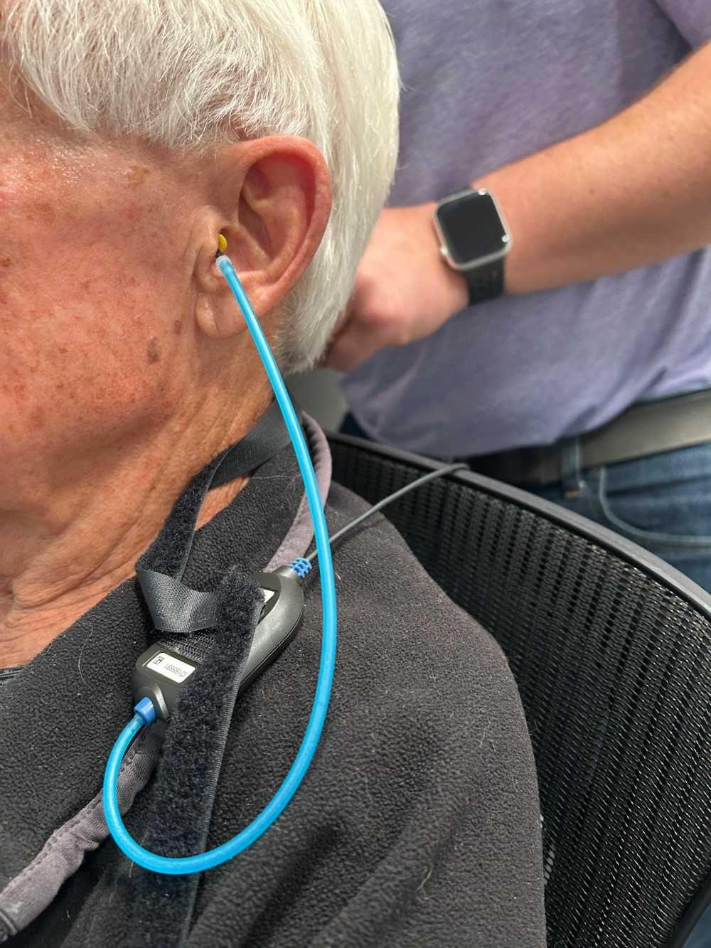 man undergoing a hearing test with tube in left ear