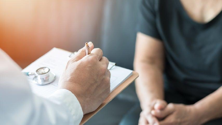 Doctor's hand writing notes on a clipboard.