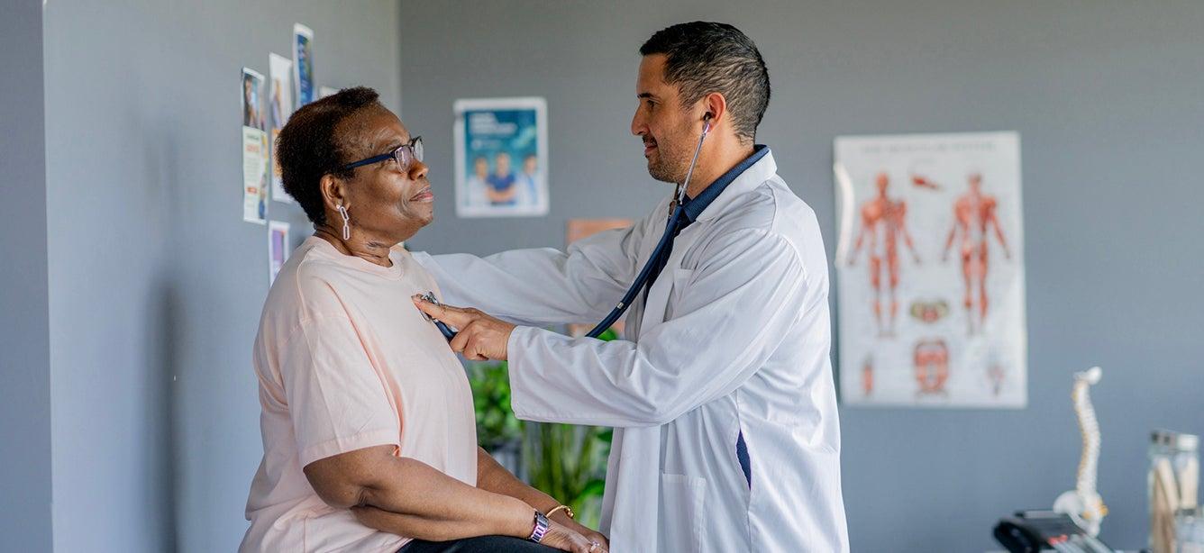 Doctor listens to woman's heartbeat with a stethoscope.