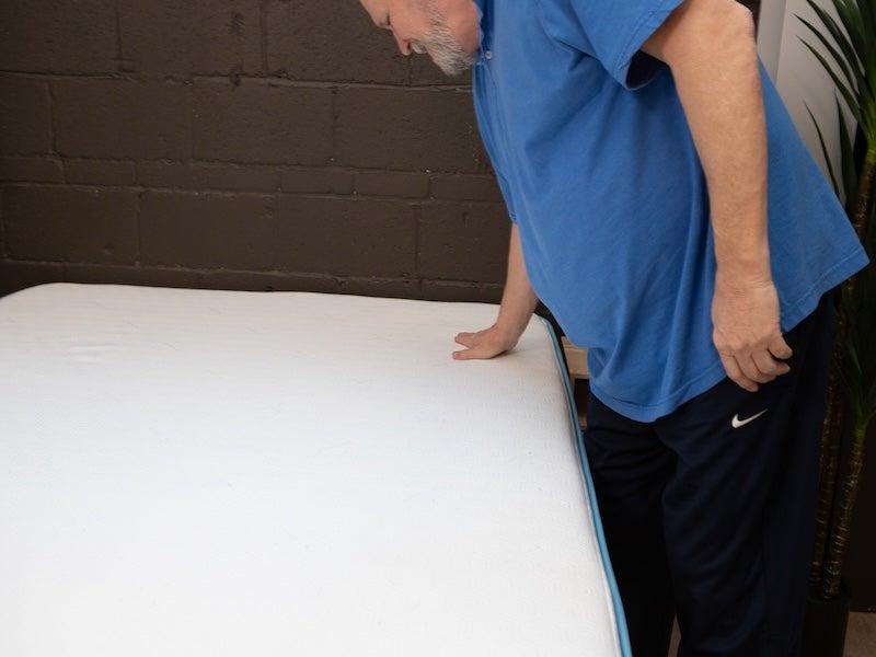 A man touches the surface of the Bear Original memory foam mattress