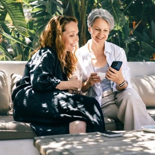 Two women look at a cell phone together and smile