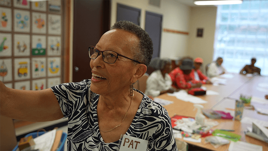 smiling older woman with Pat nametag painting in art class