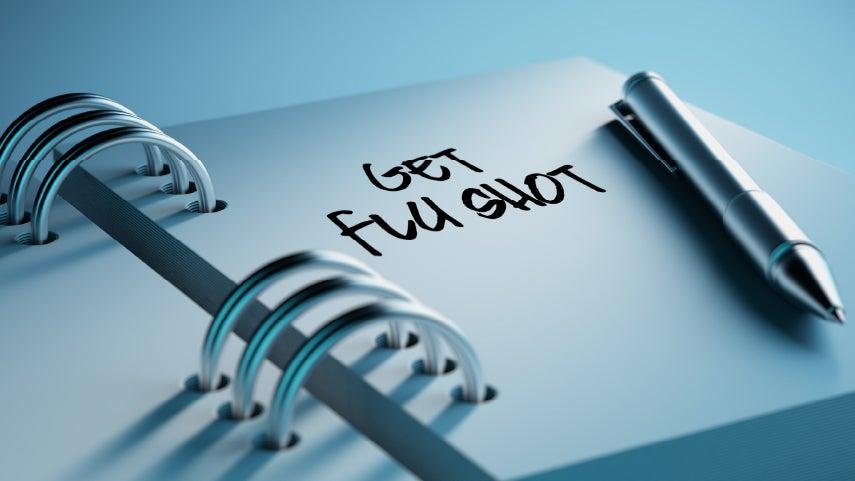 Close up shot of a spiral calendar, where the page seen says 'Get Flu Shot'.