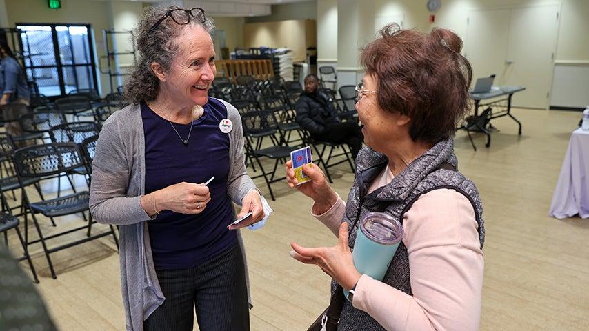 Two women talking to each other with enthusiastic expressions on their faces.
