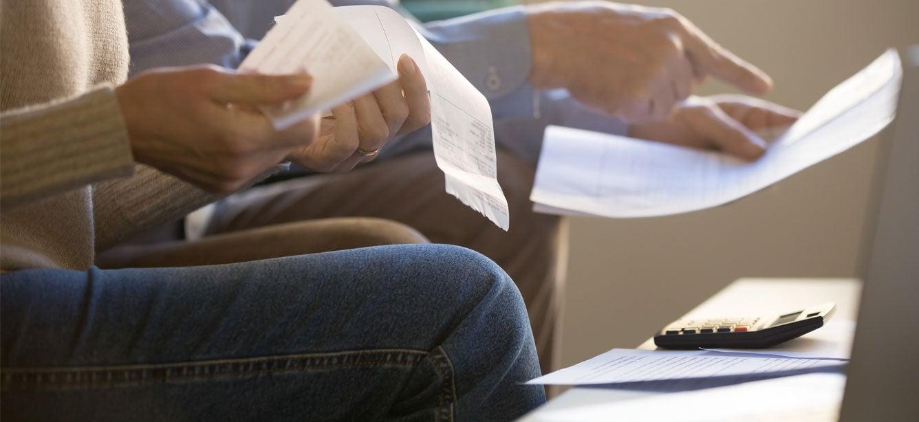 A senior couple sits on couch at home planning their budget.