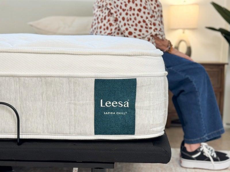 A person sitting on the edge of the Leesa Sapira Chill hybrid mattress