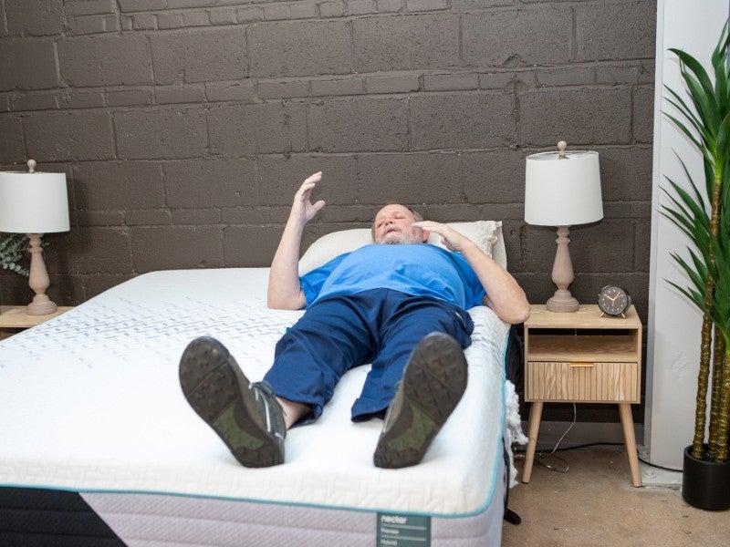 A man lays on his back on the Nectar Premier Hybrid mattress