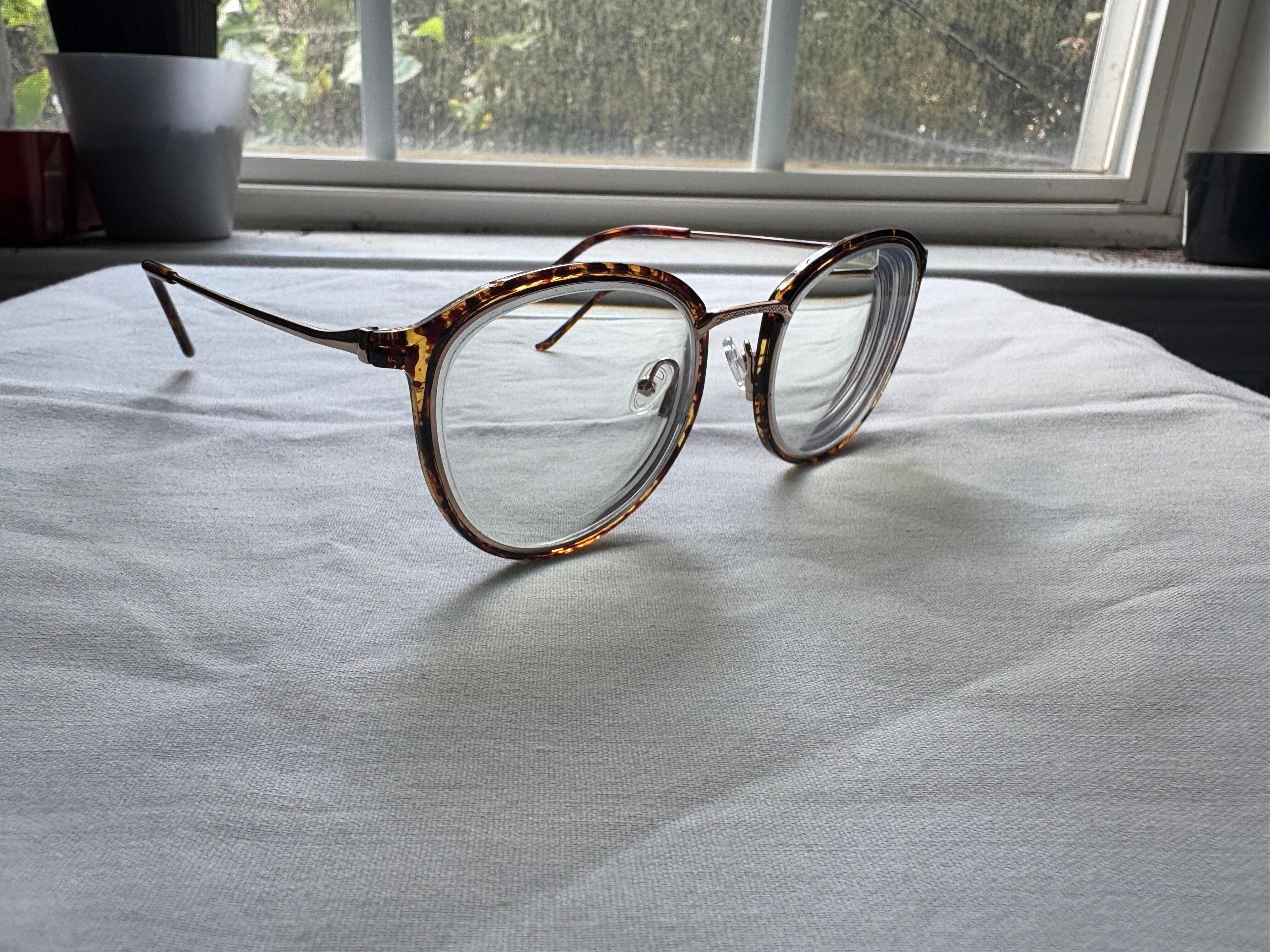 A pair of prescription eyeglasses sitting on a table in front of a window