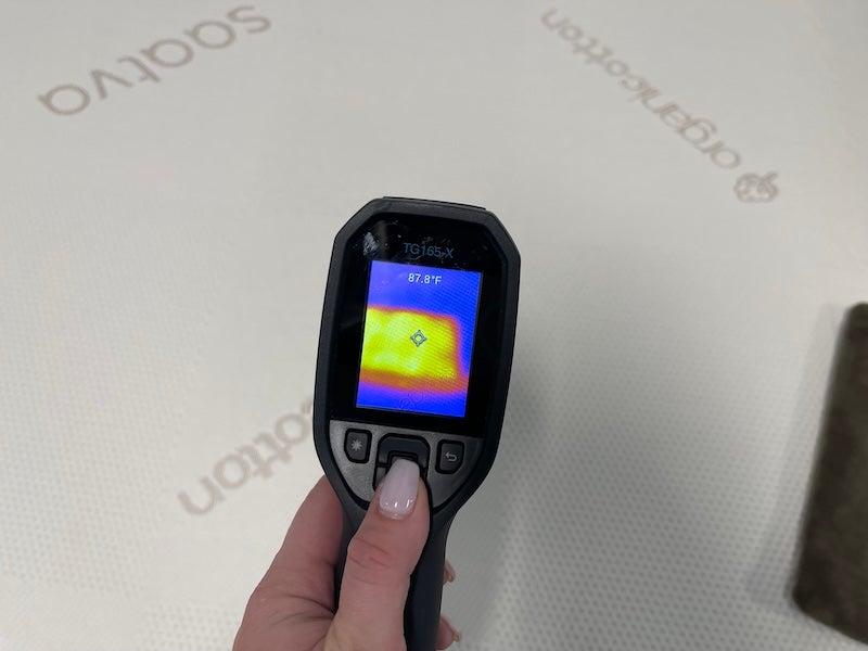 A heat gun measures the temperature of the Saatva mattress topper.