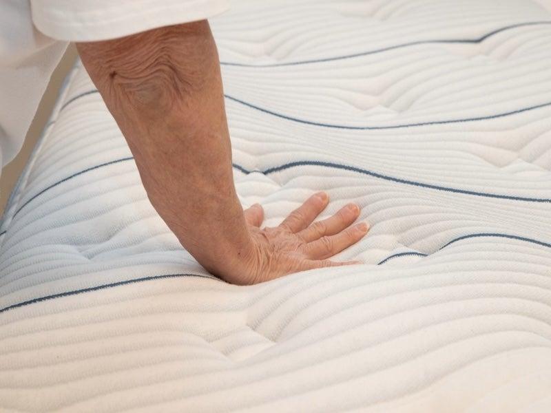 A mattress tester presses their hand into the surface of the Bear Elite Hybrid mattress