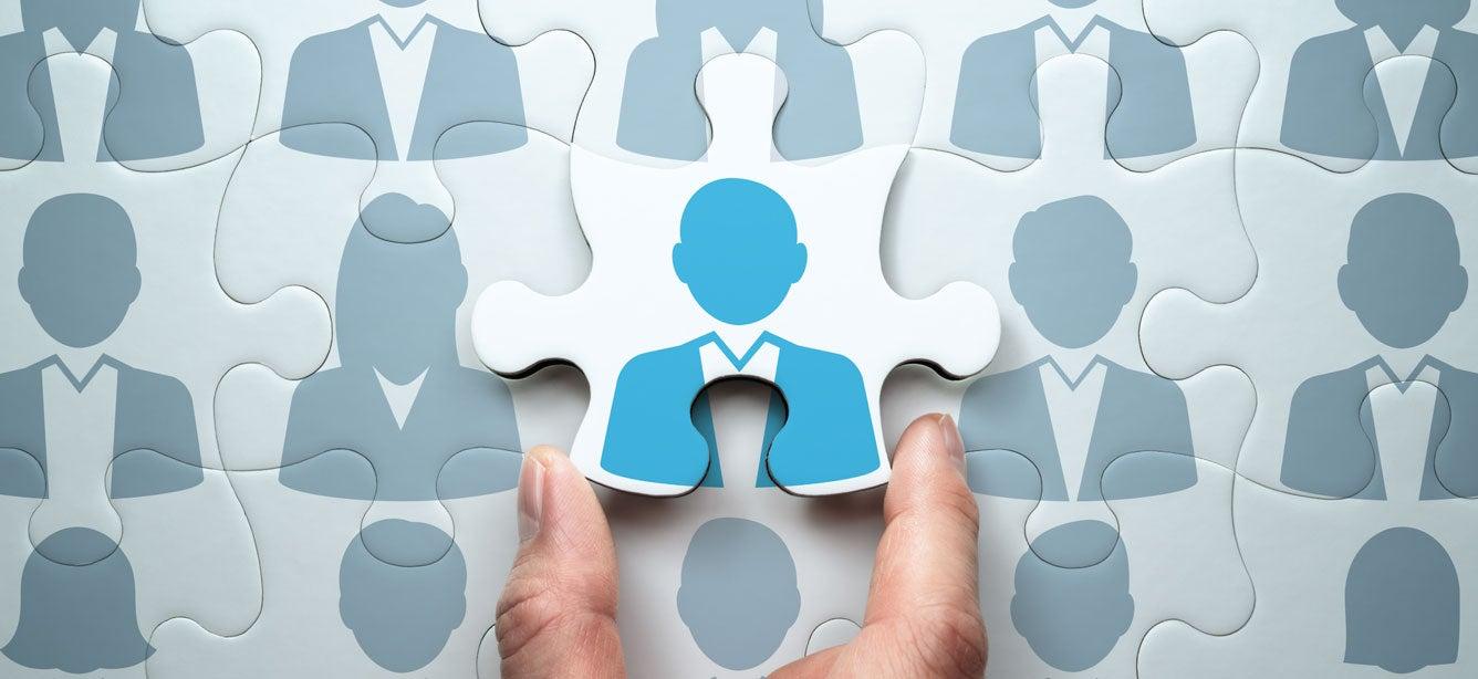 Puzzle pieces formed with images of an organizational structure, where one piece is being placed and is highlighted a different color from the others.