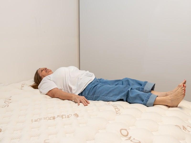 A woman lies on her back on the Saatva Rx mattress
