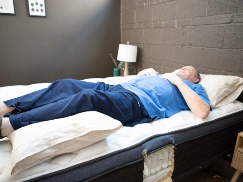 Man lying on his back with a pillow under his knees